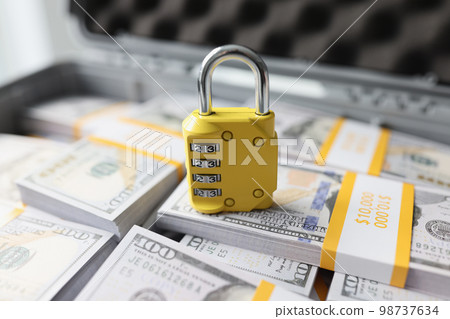 Yellow padlock with combination on many stacks of US dollars close-up. Yellow padlock with combination on many stacks of US dollars close-up. 98737634