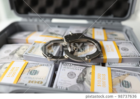 Close-up of handcuffs on stacks of dollar banknotes. Close-up of handcuffs on stacks of dollar banknotes. 98737636