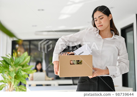 Sad Asian female office worker carrying her belonging, quitting a job, being fired from her boss. 98739644