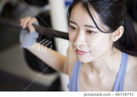 在健身房做槓鈴深蹲的年輕女子 98739741