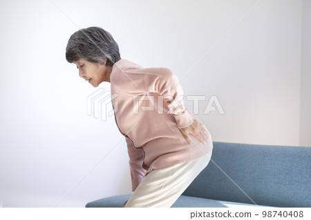 Elderly woman holding her waist and standing up Elderly woman holding her waist and standing up 98740408