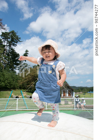 Stock image of a toddler playing happily on a trampoline in the park 98744277