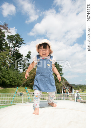 Stock image of a toddler playing happily on a trampoline in the park 98744278
