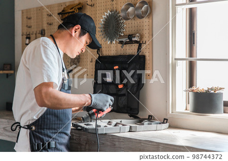 Men using tools in the garage of the house (DIY, craft, DIY, workshop, experience class, renovation) Men using tools in the garage of the house (DIY, craft, DIY, workshop, experience class, renovation) 98744372