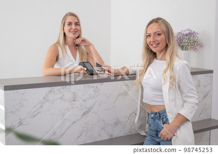 A young woman pays in a beauty salon with a credit card using NFC contactless payment.  98745253