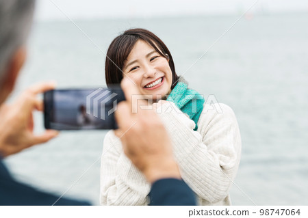 couple taking pictures by the sea 98747064