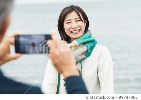 couple taking pictures by the sea 98747065