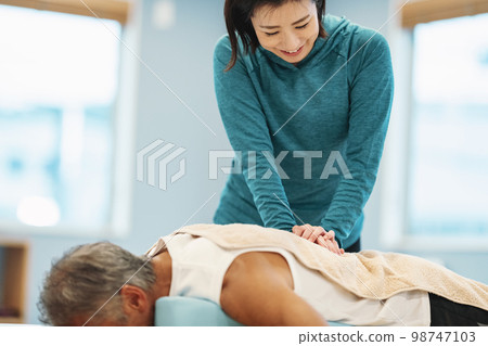 Trainer giving waist massage 98747103