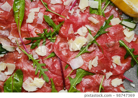 Marbled beef carpaccio on black background, closeup top view Marbled beef carpaccio on black background, closeup top view 98747369
