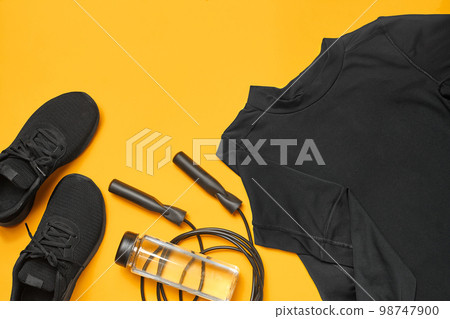 Close-up studio shot of a gym accessories on a yellow background. Top view, flat lay. Close-up studio shot of a gym accessories on a yellow background. Top view, flat lay. 98747900