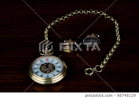 Vintage Pocket Watch and Chain with Gold Cuff Links on a Wooden Table Top 98748129