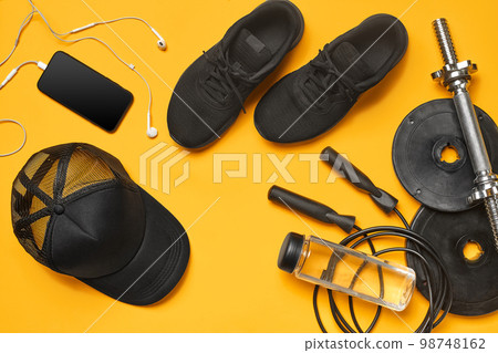 Close-up studio shot of a gym accessories on a yellow background. Top view, flat lay. Close-up studio shot of a gym accessories on a yellow background. Top view, flat lay. 98748162
