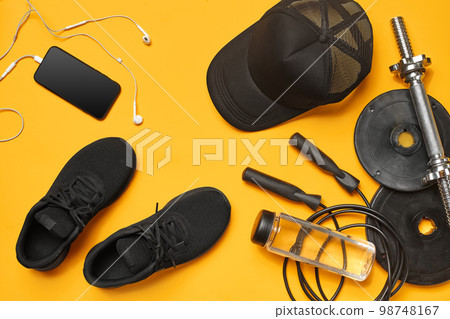 Close-up studio shot of a gym accessories on a yellow background. Top view, flat lay. 98748167