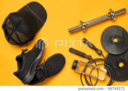 Close-up studio shot of a gym accessories on a yellow background. Top view, flat lay. 98748172