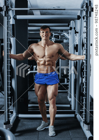 Handsome man with big muscles, posing at the camera in the gym Handsome man with big muscles, posing at the camera in the gym 98748248