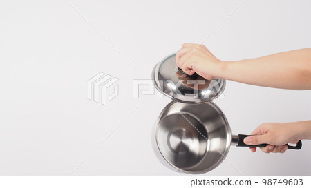 Pot cleaning Man hand on white background cleaning the non stick pot with handy dish washing sponge which yellow color on the soft side and green on hard side for hygiene after cook. Electric pot 98749603