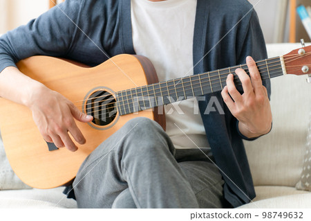 A man playing a guitar, in the living room A man playing a guitar, in the living room 98749632