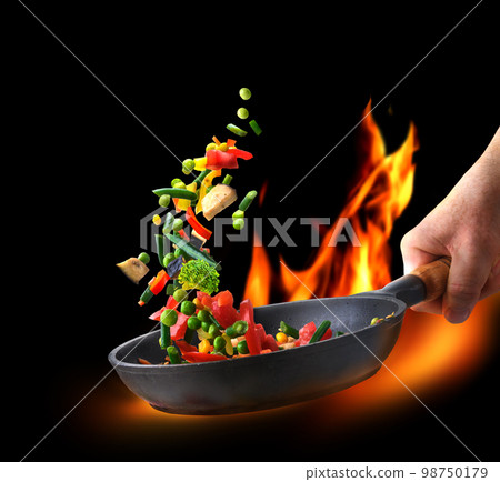 Fresh vegetables in a pan in chef hand on fire and black background 98750179