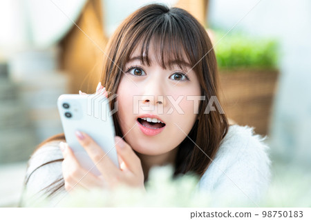 一位對智能手機感到滿意的年輕女性的特寫 98750183