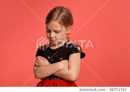 Close-up shot of a charming blonde little lady in a combined dress posing against a pink background. 98751581