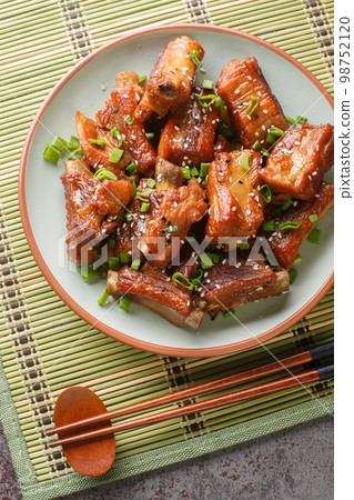 Homemade Chinese pork short ribs in sweet and sour sauce close-up in a plate. Vertical top view 98752120