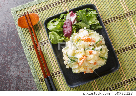 Classic  home-cooked dish Japanese Potato Salad is distinct because of its colorful addition of fresh vegetables, creamy texture and rounded flavor close-up in a plate. Horizontal top view 98752128