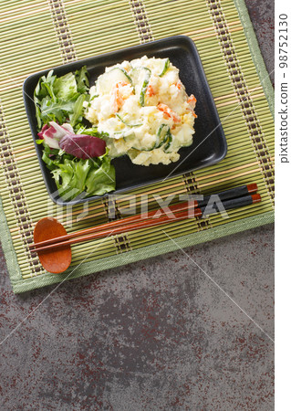 Traditional Japanese creamy potato salad with carrots, eggs and fresh cucumber close-up in a plate. Vertical top view Traditional Japanese creamy potato salad with carrots, eggs and fresh cucumber close-up in a plate. Vertical top view 98752130