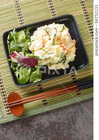 Japanese potato salad with carrots, eggs and fresh cucumber close-up in a plate. Vertical top view Japanese potato salad with carrots, eggs and fresh cucumber close-up in a plate. Vertical top view 98752131