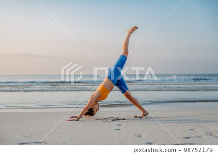 Young woman taking exercises at beach, morning routine and healthy lifestyle concept. 98752179