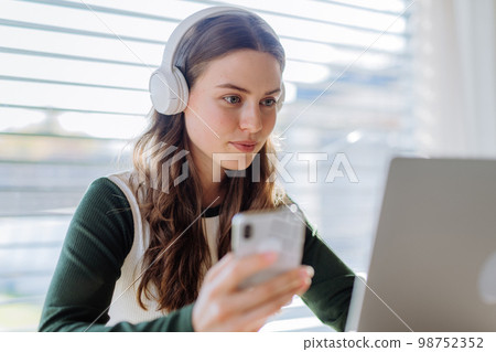 Young woman having distance education in her apartment. 98752352