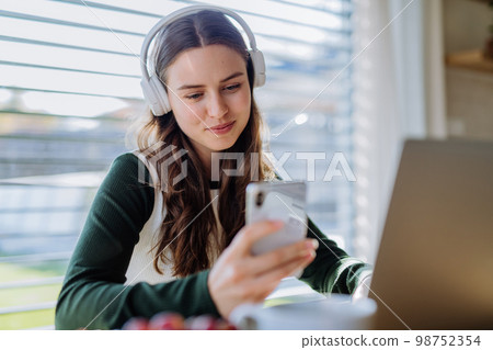 Young woman having distance education in her apartment. 98752354