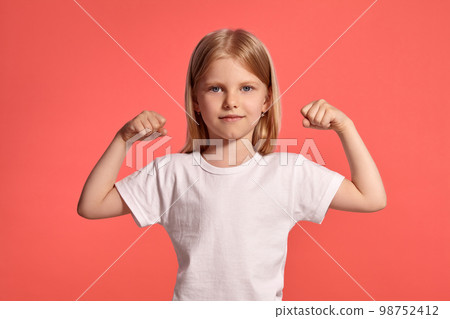 Close-up studio shot of a nice blonde little girl in a white t-shirt posing against a pink background. Close-up studio shot of a nice blonde little girl in a white t-shirt posing against a pink background. 98752412