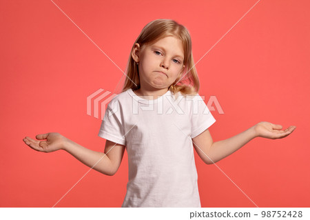 Close-up studio shot of a nice blonde little girl in a white t-shirt posing against a pink background. Close-up studio shot of a nice blonde little girl in a white t-shirt posing against a pink background. 98752428