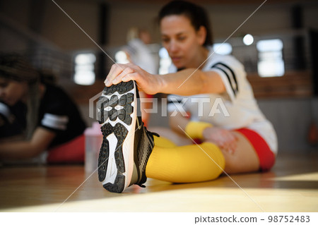 Happy women stretching before basketball match in gym. 98752483