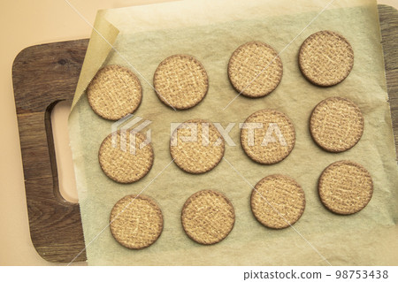 Freshly baked homemade sesame seed cookies on wooden board, rustic table. Healthy, tasty snack, honey seed bar, round form biscuits. Organic dessert, top view in row 98753438