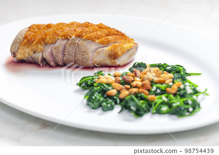 roasted duck breast served with salad of spinach leaves and pine nuts 98754439