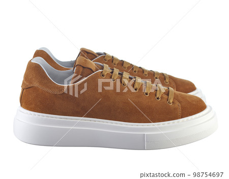 Side view fashionable modern sneakers made of reddish-yellow suede, lace-up, with a massive shock-absorbing sole, isolated on a white background. Side view fashionable modern sneakers made of reddish-yellow suede, lace-up, with a massive shock-absorbing sole, isolated on a white background. 98754697