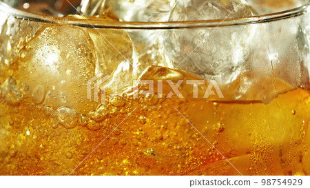 Detail of cider with ice cubes in glass. 98754929