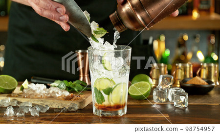 Preparation of mojito drink on bar counter. 98754957