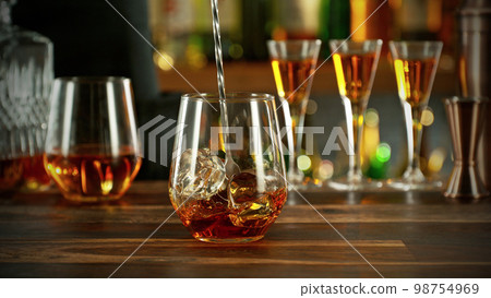 Detail of stiring whiskey glass with ice. 98754969