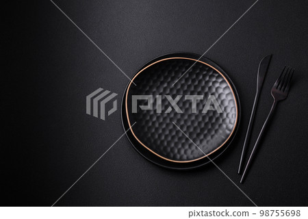 Empty ceramic round plate on dark textured concrete background Empty ceramic round plate on dark textured concrete background 98755698