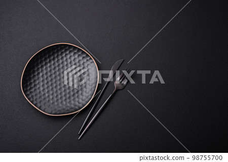 Empty ceramic round plate on dark textured concrete background Empty ceramic round plate on dark textured concrete background 98755700
