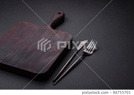 Empty wooden cutting board on dark textured concrete background Empty wooden cutting board on dark textured concrete background 98755701