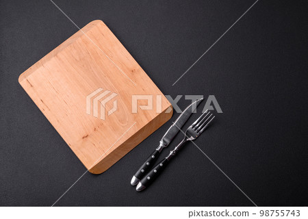 Empty wooden cutting board on dark textured concrete background Empty wooden cutting board on dark textured concrete background 98755743
