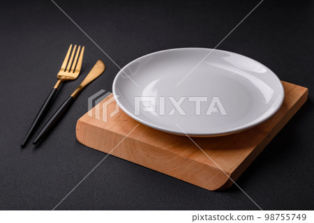 Empty ceramic round plate on dark textured concrete background Empty ceramic round plate on dark textured concrete background 98755749