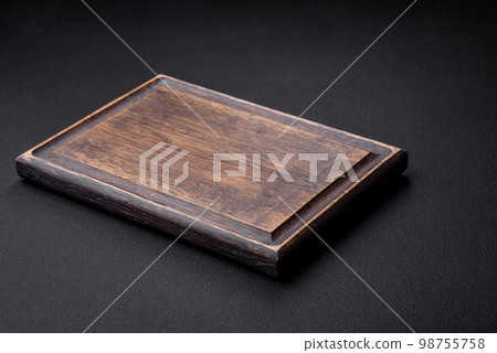 Empty wooden cutting board on dark textured concrete background 98755758