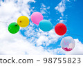 Party balloons in front of a cloudy sky. 98755823