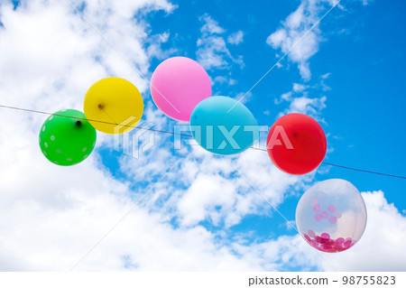 Party balloons in front of a cloudy sky. 98755823