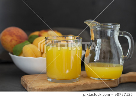 Fresh fruit juice. Apricots and peaches. Fresh and healthy juice in a glass and decanter on a kitchen board. copy space 98757125