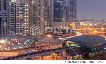 Futuristic building of Dubai metro station and luxury skyscrapers behind in Dubai Marina aerial day to night 98757257